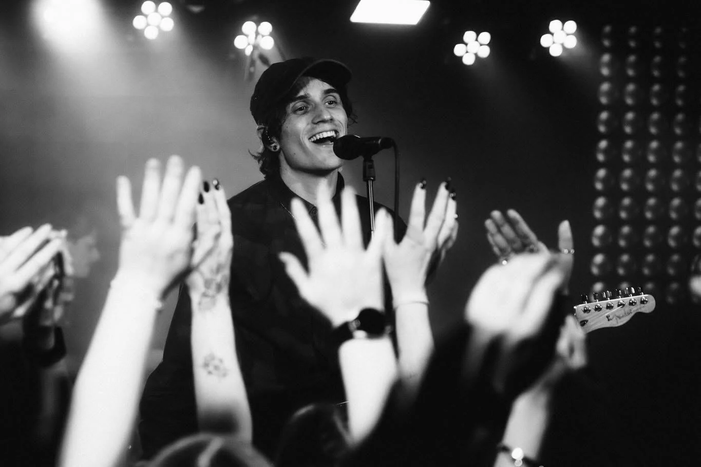 A singer at a microphone with raised hands in the foreground