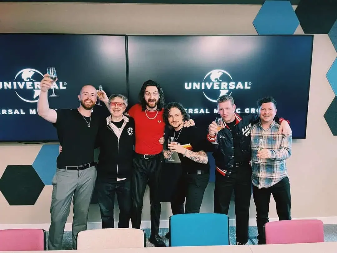 A group celebrating together in front of Universal Music screens